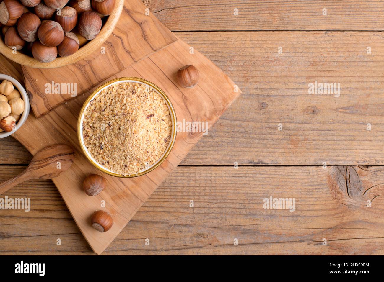 Raw Organic Ground Hazelnut Flour in a Bowl with whole nuts on rustic