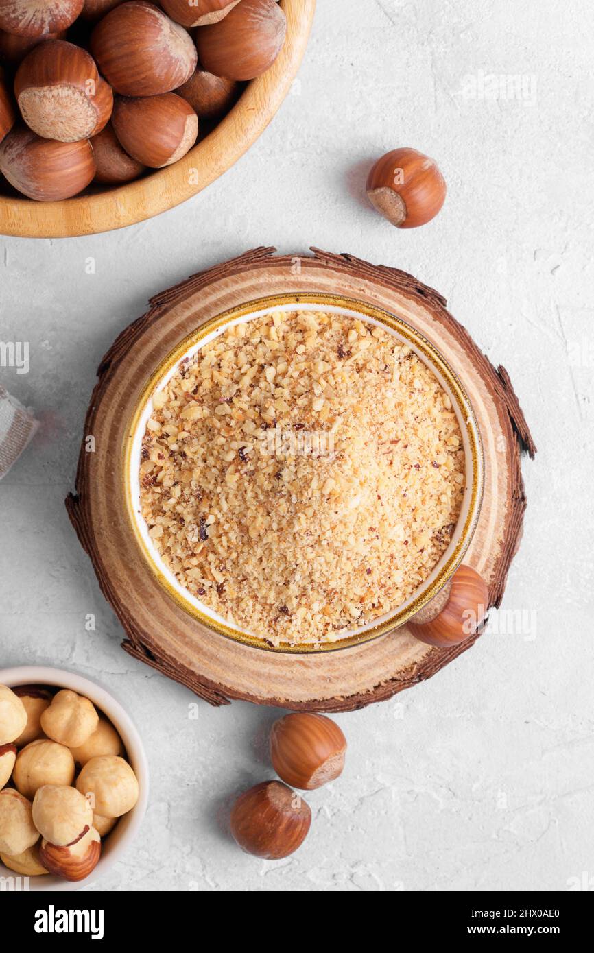 Raw Organic Ground Hazelnut Flour in a Bowl with whole nuts on grey