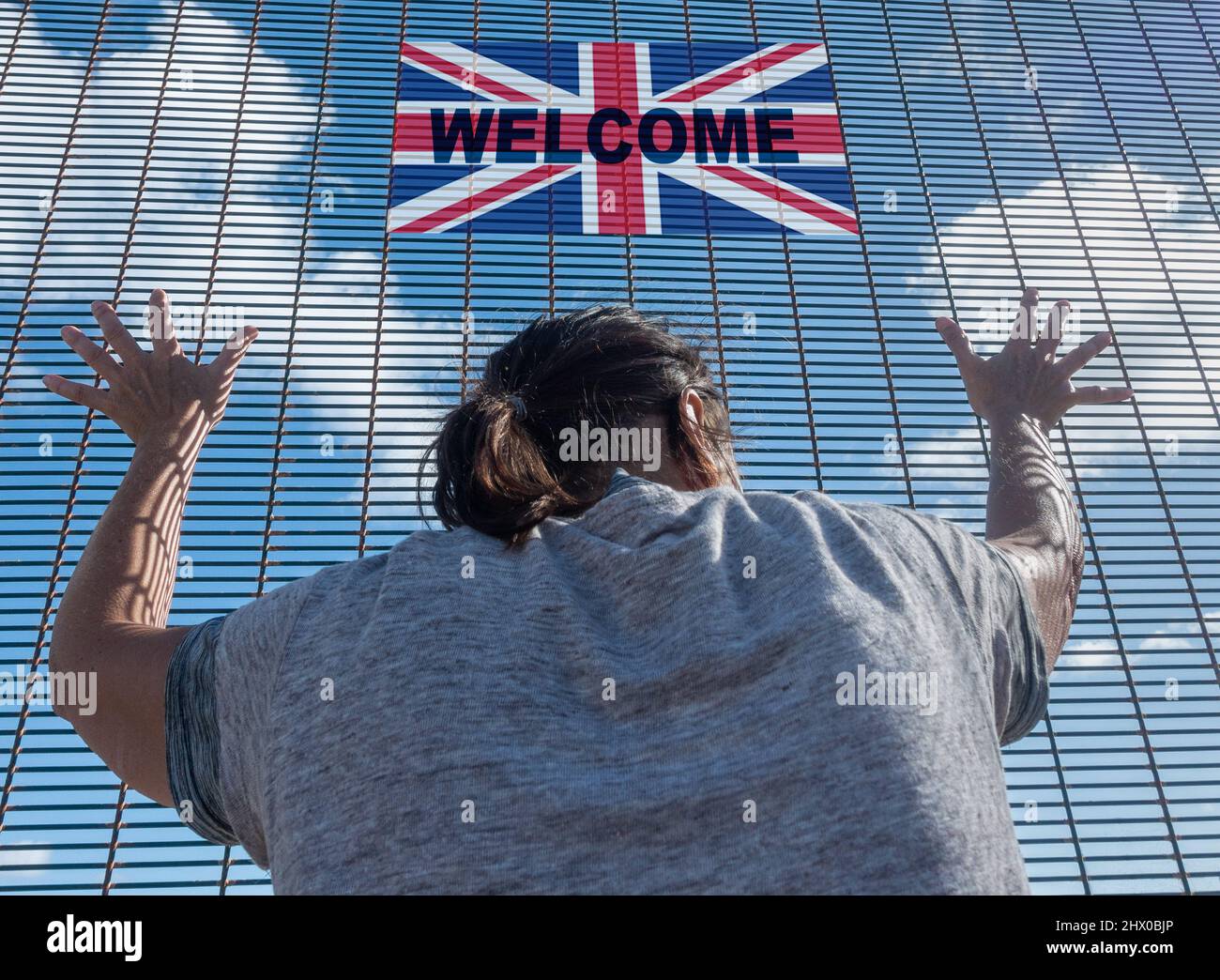 Rear view of woman at border fence control with UK flag. UK immigration, visa policy, Ukraine, Russia conflict refugee, Brexit, EU border... concept Stock Photo