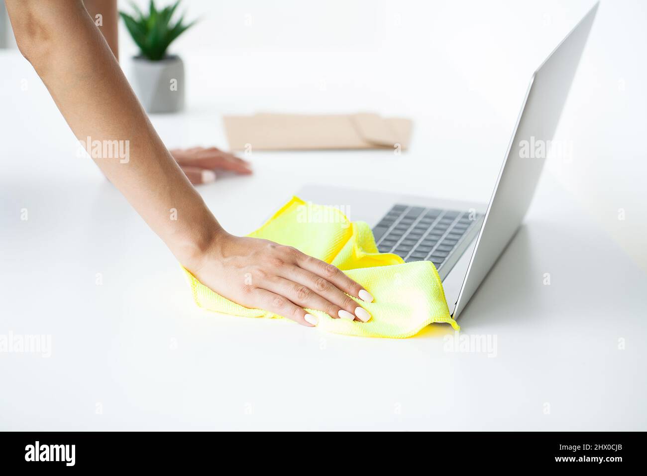 Woman disinfecting laptop keyboard with wet disinfectant wipes Stock