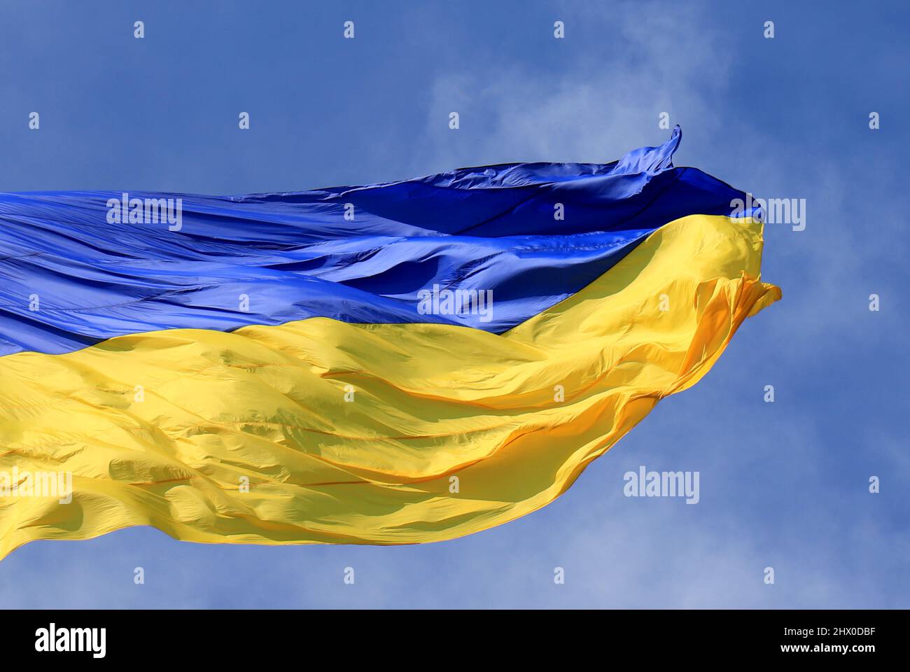 Ukraine flag large national symbol fluttering in blue sky. Large yellow blue Ukrainian state patriotic flag Stock Photo