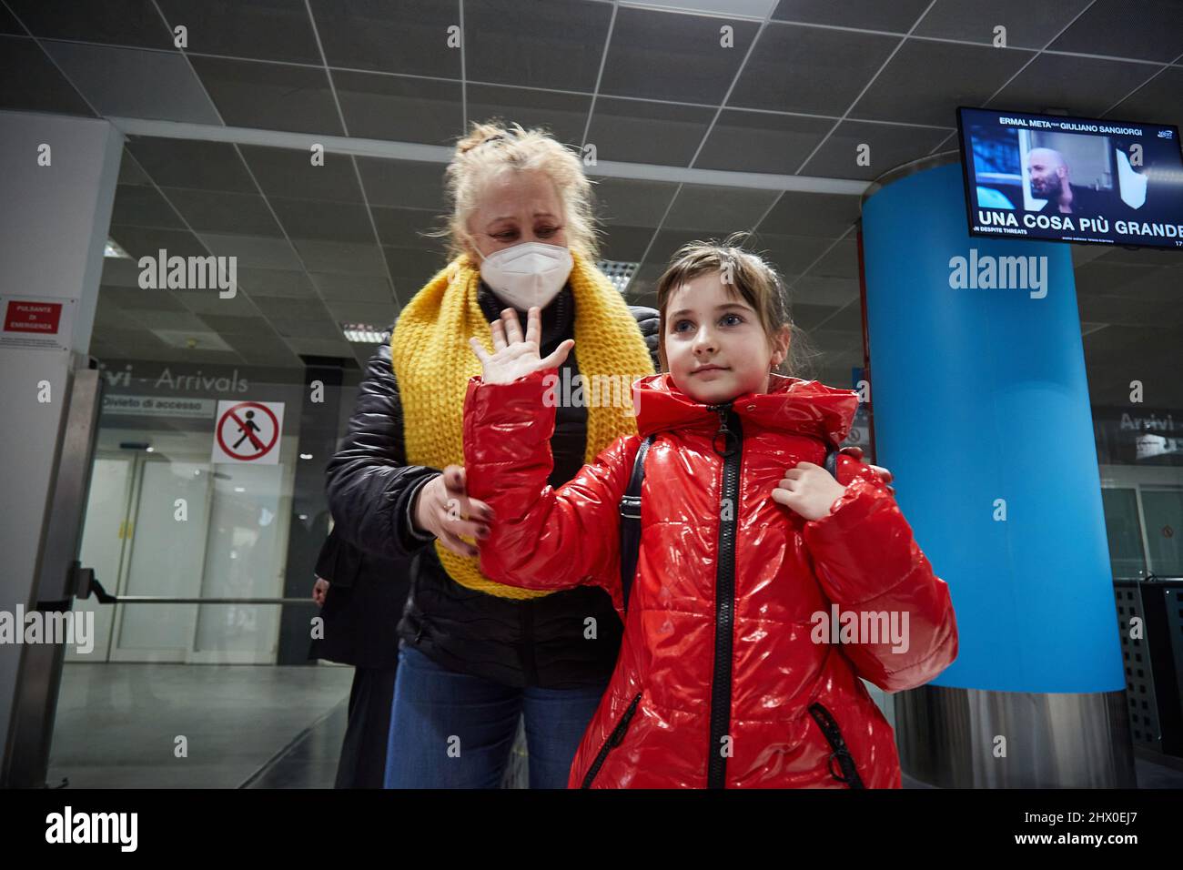 Palermo, Sicily, Italy. 8th Mar, 2022. Arrival of the first Ukrainian refugees in Palermo.The flight, from Krakow, Poland, landed around 5:00 p.m. at the Falcone Borsellino airport in Punta Raisi, Palermo.Upon arrival, refugees, welcomed by relatives and UNHCR volunteers, have carried out the anti-COVID protocol before leaving the airport. Ukrainian girl greets the press with her grandmother. (Credit Image: © Victoria Herranz/ZUMA Press Wire) Stock Photo