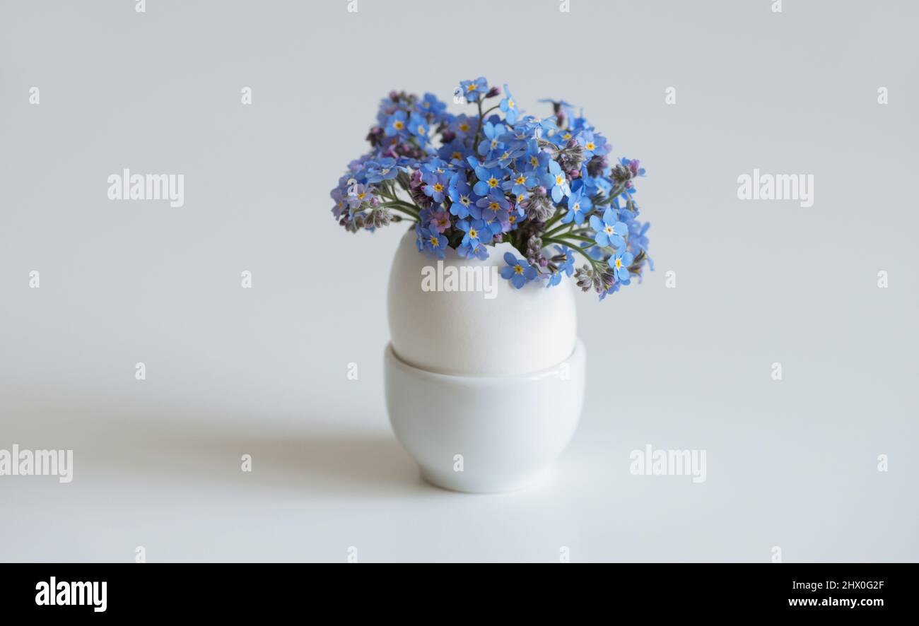 Small white egg with flowers bouquet on a white background. Easter egg. Space for text. Stock Photo