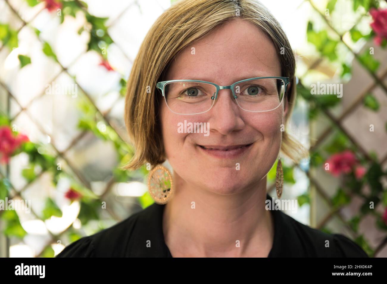 Portrait of a thirty year old white caucasian lady with glass, golden earrings and a black dress, Brussels Stock Photo
