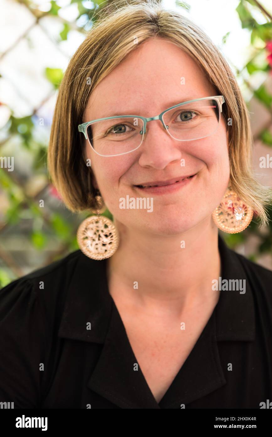 Portrait of a thirty year old white caucasian lady with glass, golden earrings and a black dress, Brussels Stock Photo