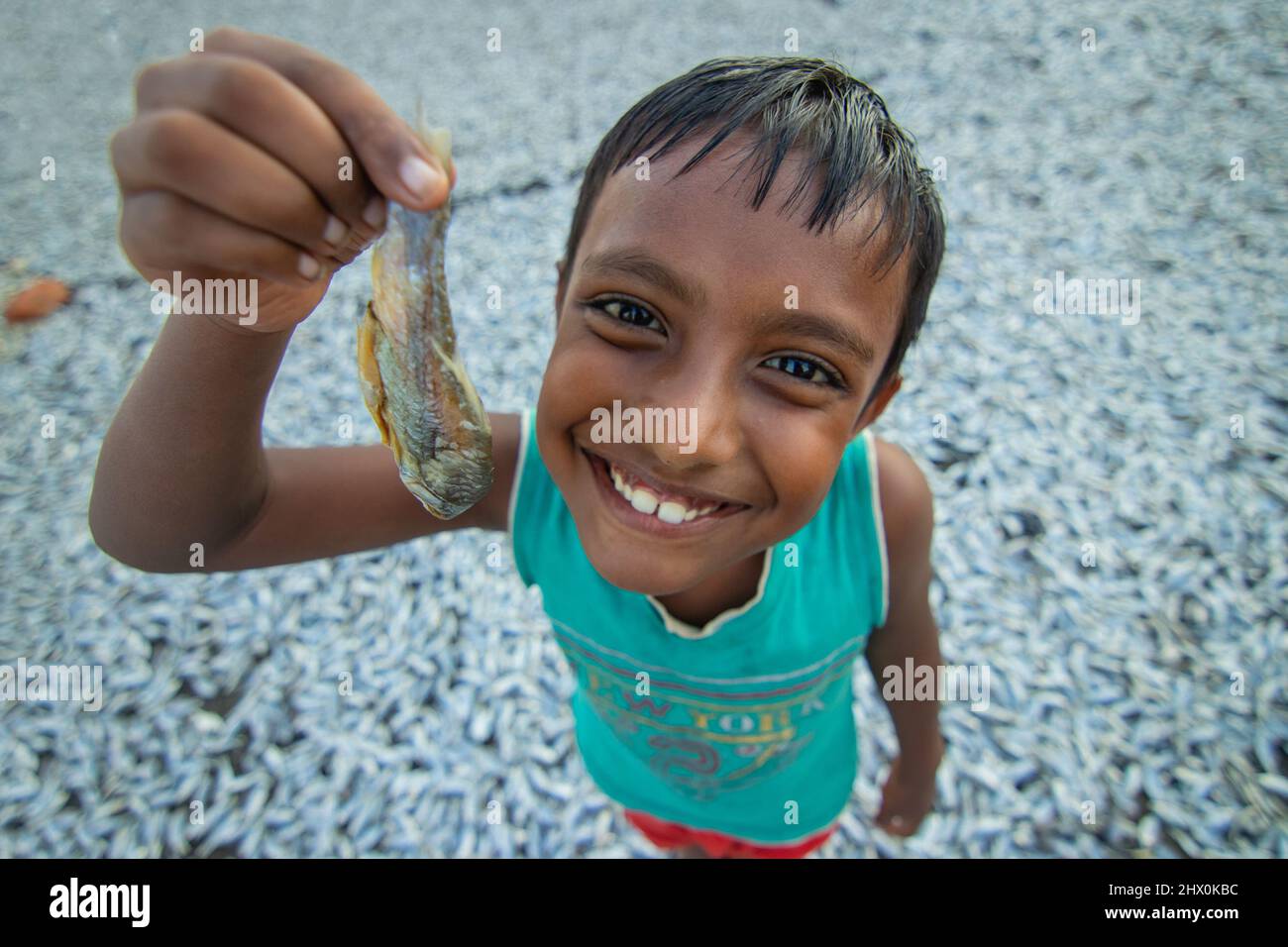 Brahmanbaria, Chittagong, Bangladesh. 8th Mar, 2022. A child worker is showing a ''Puti'' fish in a dry fish processing area in Brahmanbaria, Bangladesh. There is a high prevalence of employing child labor in dry fish processing sector as children can be paid less. Each child gets up to only 200 BDT (approximately 2 euro) per day after working for 6-8 hours at a stretch. (Credit Image: © Joy Saha/ZUMA Press Wire) Stock Photo