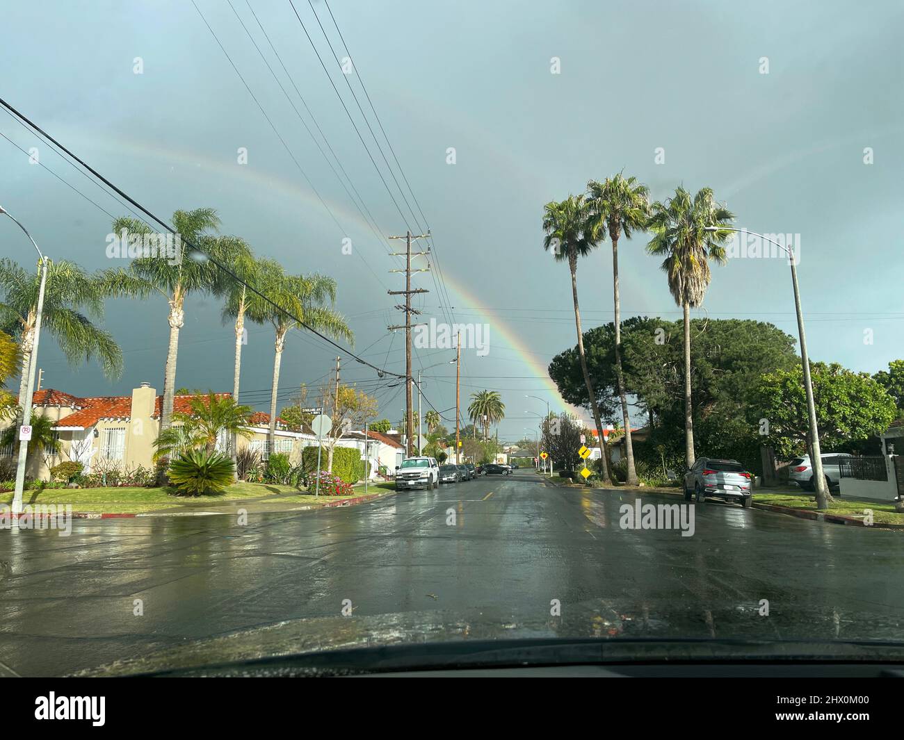 View through windshield of car driving on rainy day with a rainbow in Los Angeles, CA Stock Photo