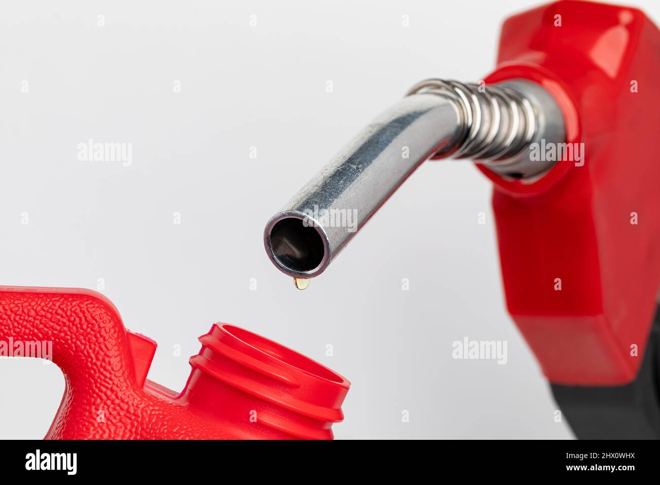 Gas dripping from fuel nozzle into gas can. Gasoline shortage, price and ethanol concept. Stock Photo