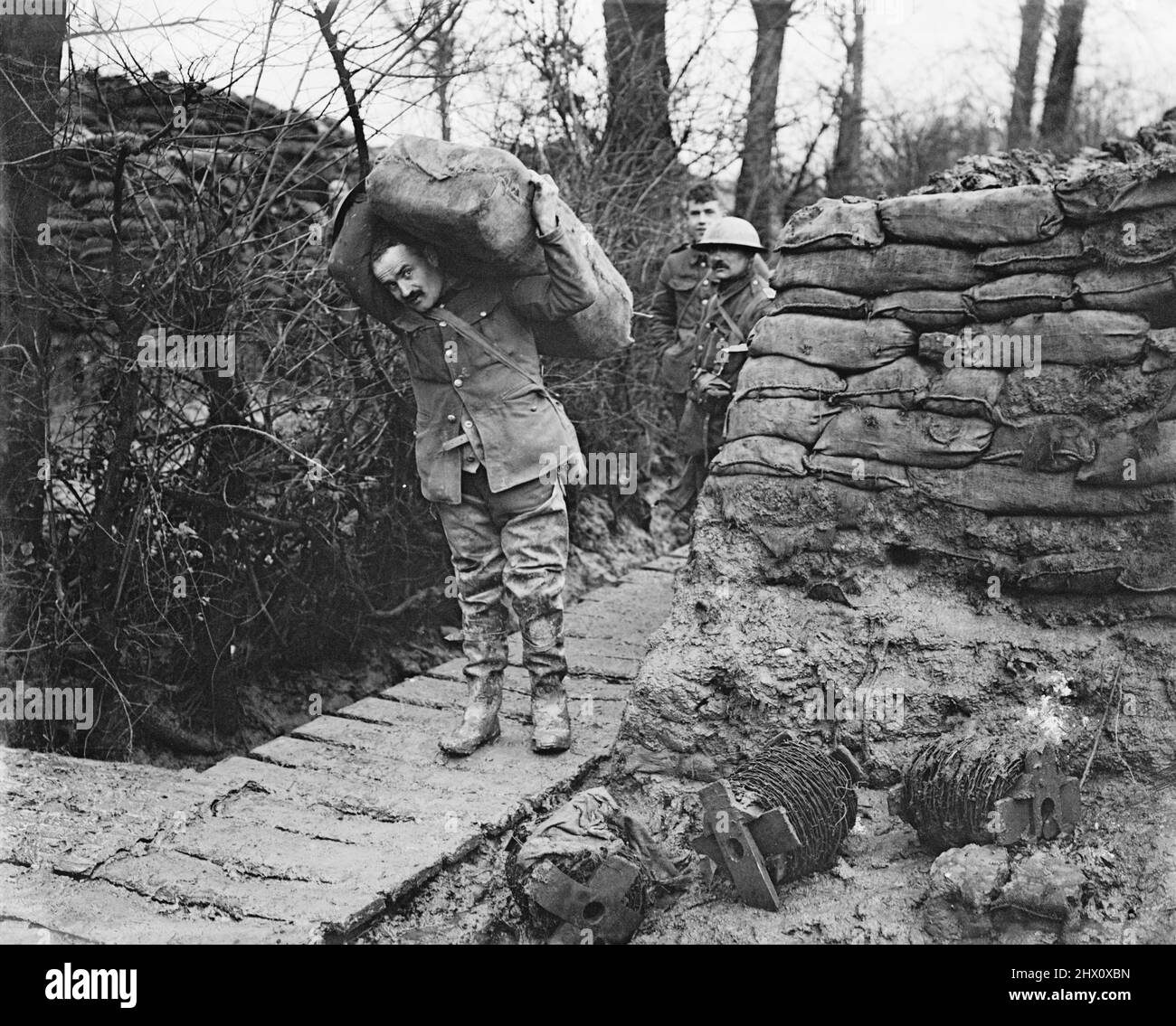 Lancashire Fusilier wearing waders taking a load of sandbags up a communication trench. Ploegsteert Wood, January 1917. Stock Photo