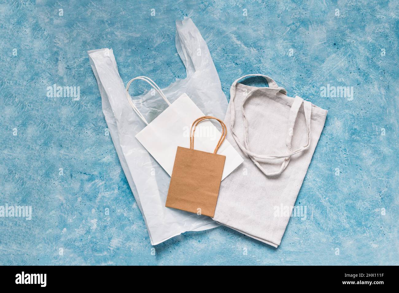 single use plastic bag next to paper and reusable canvas ones, plastic