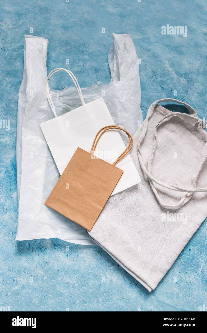 single use plastic bag next to paper and reusable canvas ones, plastic