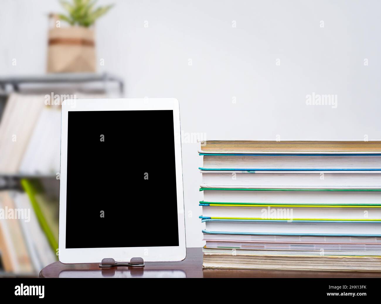 Tablet with copy space next to stack of books on table Stock Photo