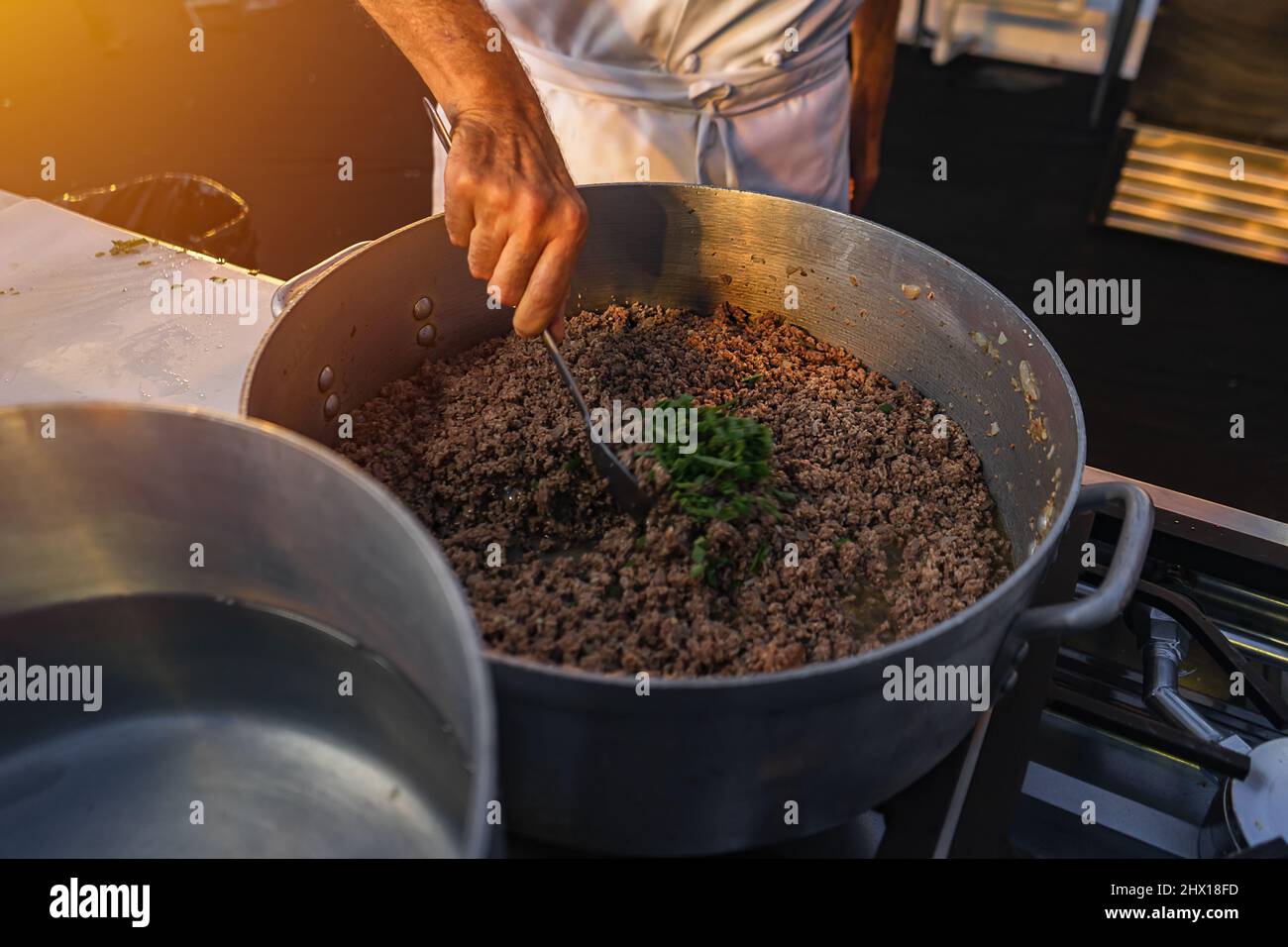Closeup of a chef's hand stirring ground beef with oregano Stock Photo