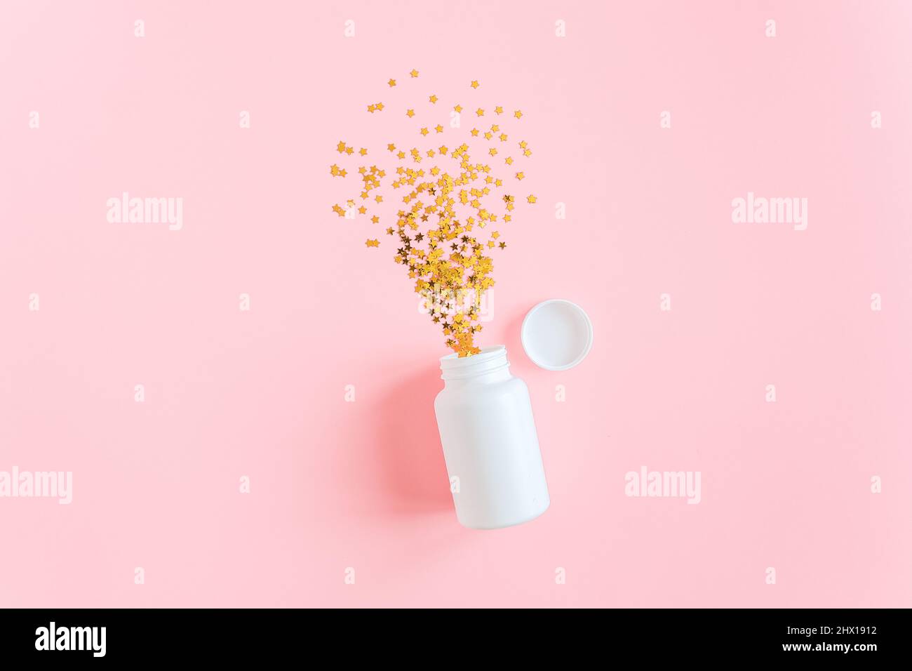 Gold stars confetti fly out white medical bottle on pink background. Concept sleeping pills, melatonin for insomnia, therapy with antidepressants for Stock Photo