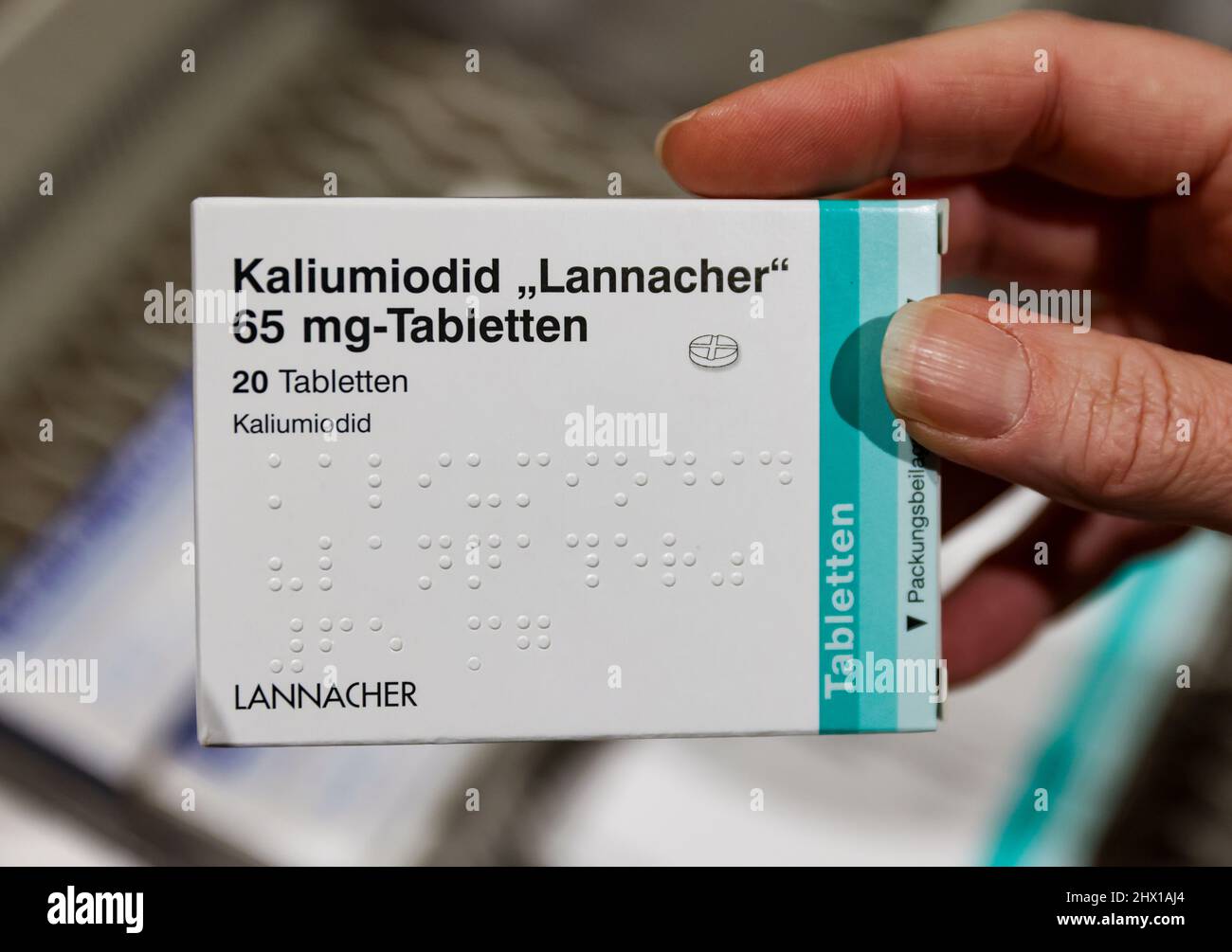 08 March 2022, Saxony, Leipzig: A pharmacist takes a pack of high-dose iodine tablets from a supply cabinet. The increased demand for iodine tablets in view of the war in Ukraine could lead to problems for patients with thyroid diseases. Certain preparations are no longer available, the Saxon Pharmacists Association informed on request - and warned against a preventive intake of low-dose iodine tablets. The authorities responsible for disaster control have stockpiled around 190 million tablets in significantly stronger doses for this purpose. Photo: Jan Woitas/dpa-Zentralbild/dpa Stock Photo