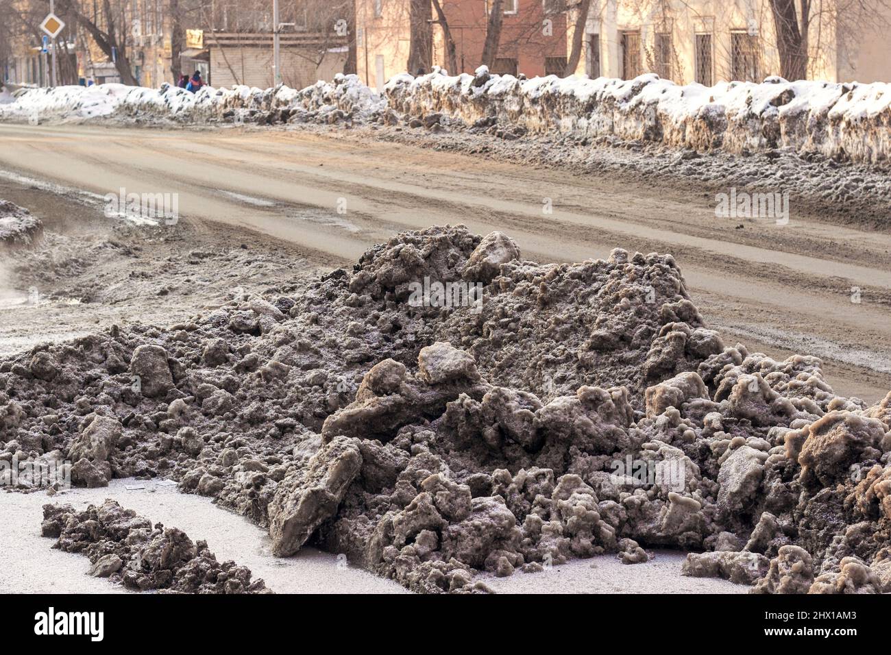 Piles of dirty snow on the streets of the city in Siberia. Sand and reagents against icy condition. Stock Photo