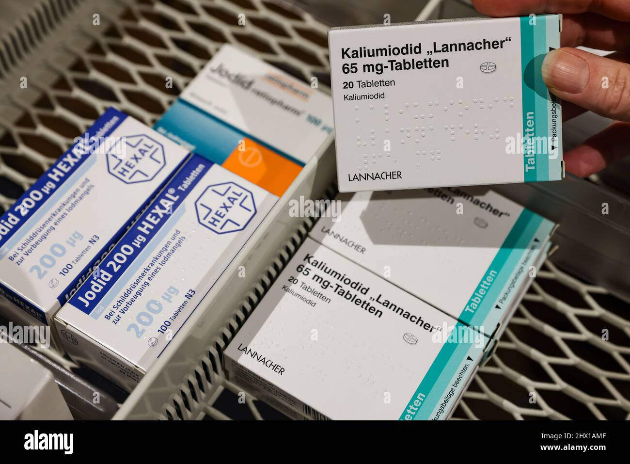 08 March 2022, Saxony, Leipzig: A pharmacist takes a pack of high-dose iodine tablets from a supply cabinet, next to which are weaker doses for thyroid disorders. The increased demand for iodine tablets due to the war in Ukraine could lead to problems for patients with thyroid diseases. Certain preparations are no longer available, the Saxon Pharmacists Association informed on request - and warned against a preventive intake of low-dose iodine tablets. The authorities responsible for disaster control have stockpiled around 190 million tablets in significantly stronger doses for this purpose. P Stock Photo