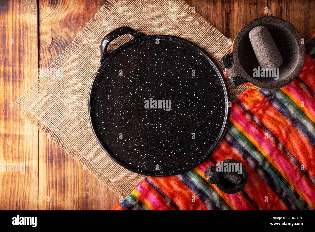 https://c8.alamy.com/comp/2HX1C7E/mexican-kitchen-utensils-colorful-traditional-fabric-comal-de-peltre-and-molcajete-on-wooden-rustic-table-top-view-with-copy-space-2HX1C7E.jpg