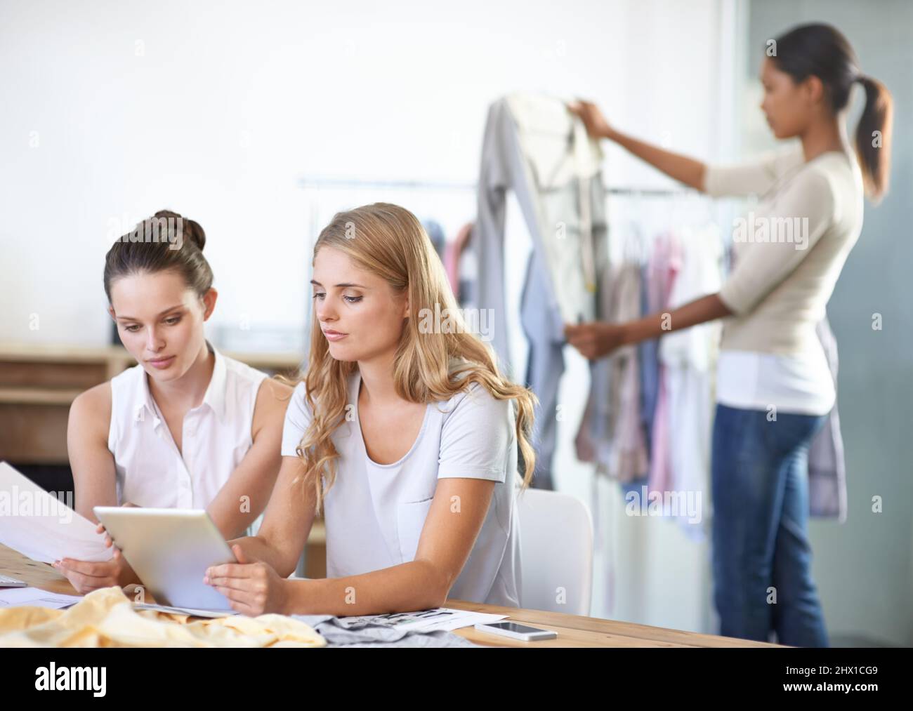 Designing the new range. Three young multi-ethnic fashion designers working in their studio. Stock Photo