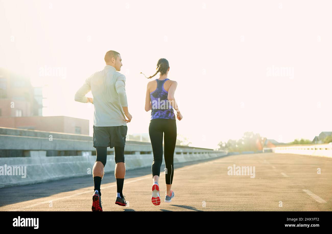 Nothing better than a morning run. Rearview shot of two friends jogging through the city. Stock Photo