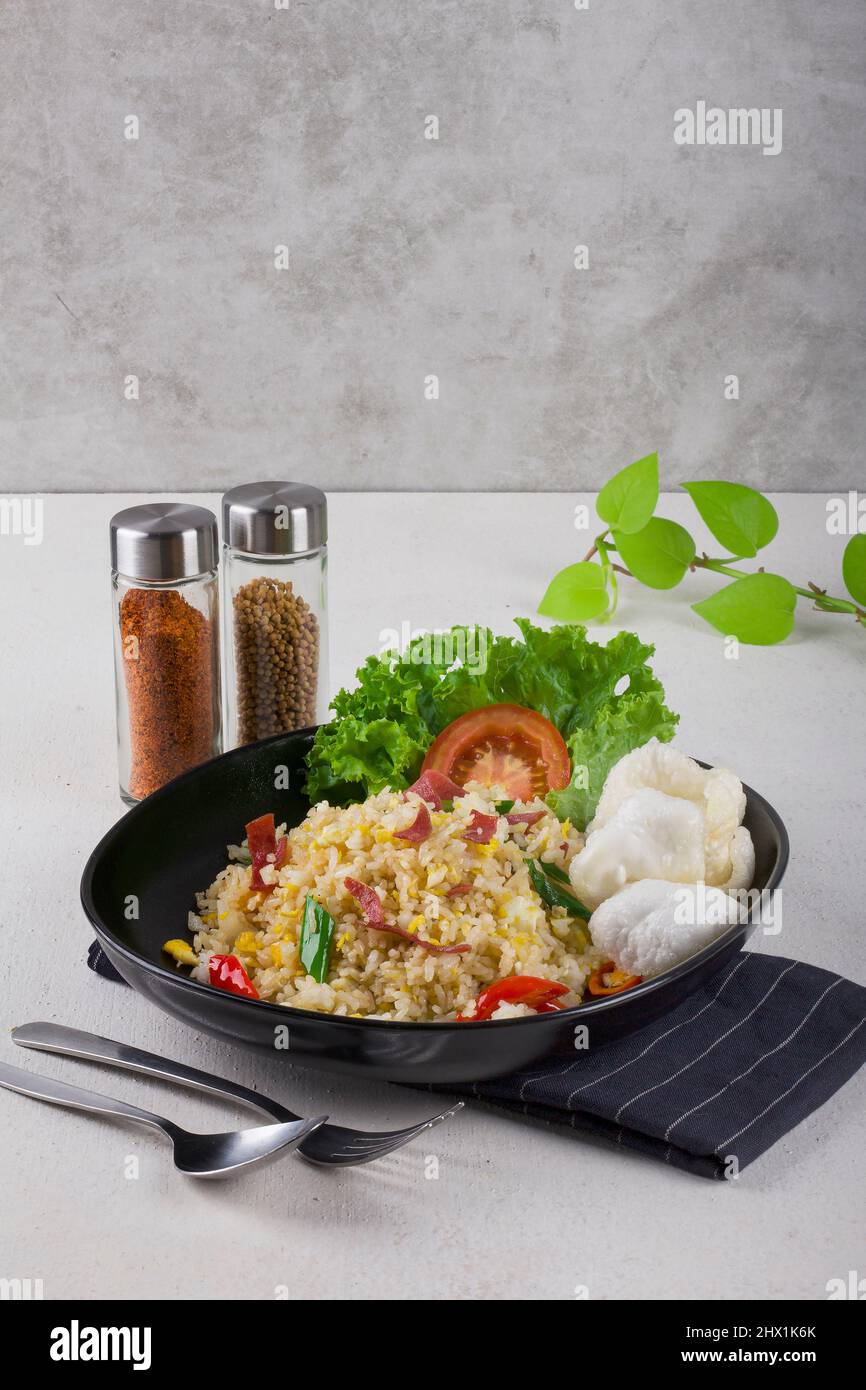 spicy asian fried rice stir fry with beef, slice fresh red tomato, fresh green lettuce and white crackers in black oval plate with blue napkin Stock Photo