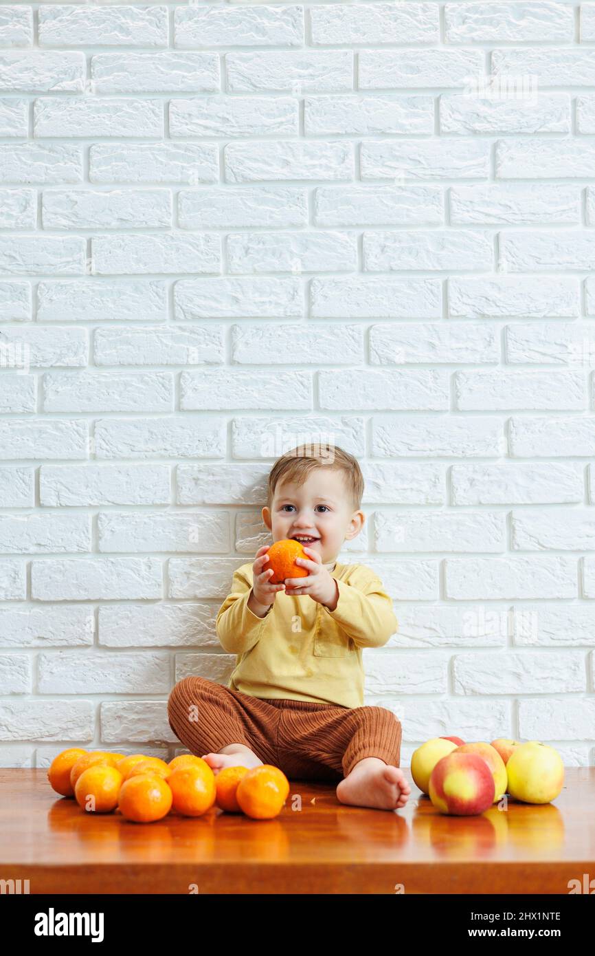 Smiling child eats one fresh juicy red apple. Healthy fruits for young