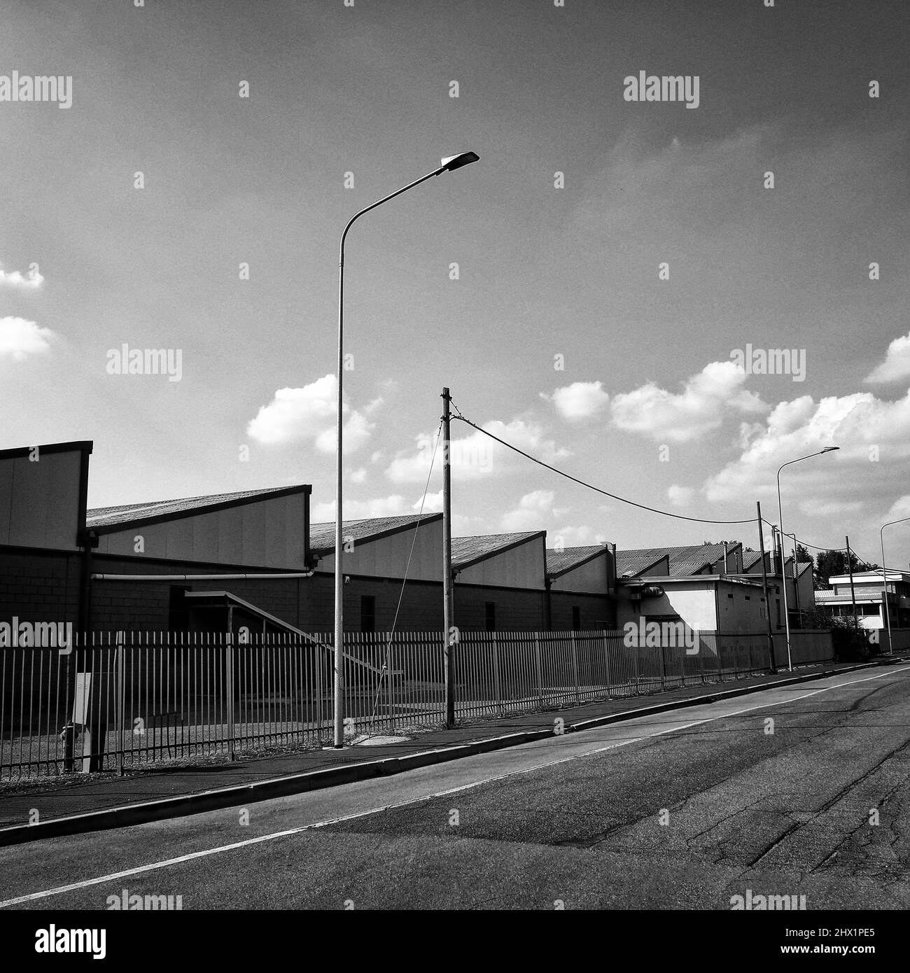 Industrial shed with white clouds in the sky - Black and white fine art photography Stock Photo