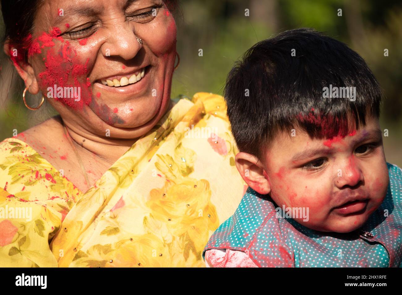 Elderly Indian Lady And Kid Enjoying Holi With Gulal Or Abir Rang Abeer. Festive, Family, Fun, Celebration, Enjoyment, Togetherness, Multi Generation, Stock Photo