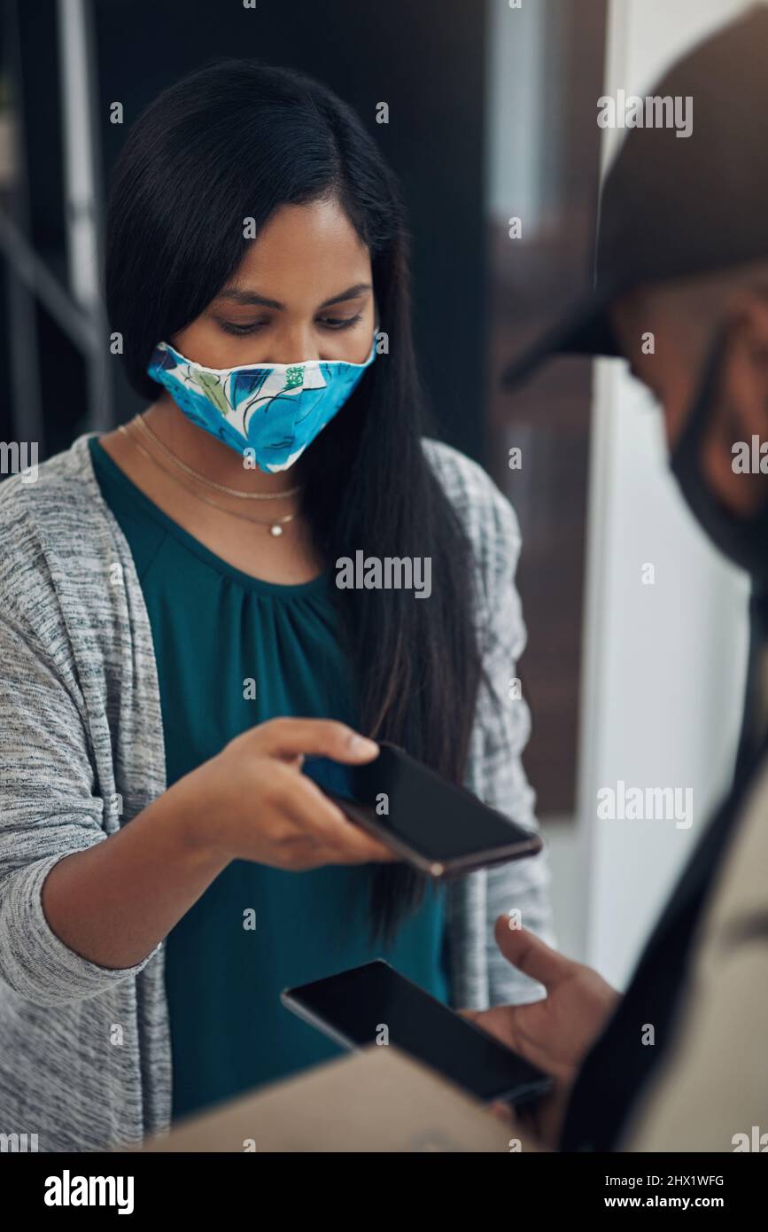 Stay safe, pay with your phone. Shot of a masked young man and woman ...