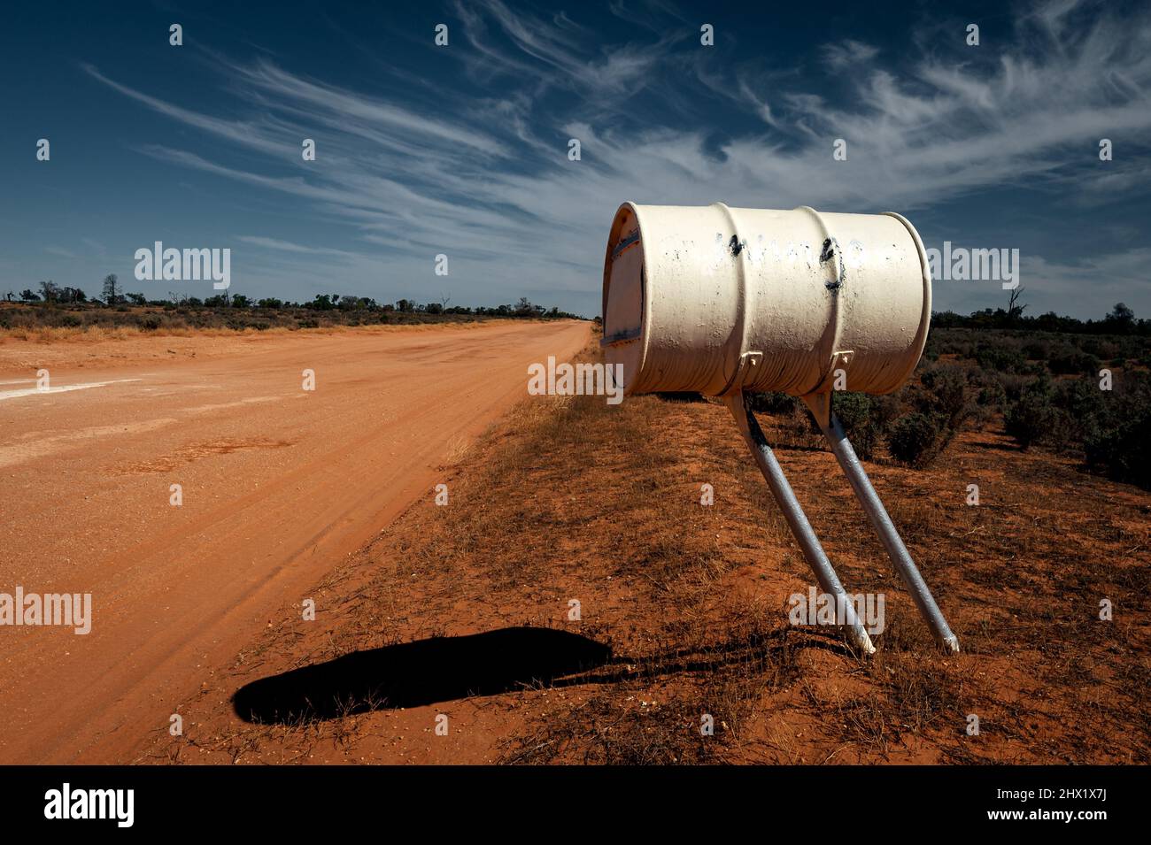 Barrel mailbox of Mungo National Park at a red outback gravel road. Stock Photo