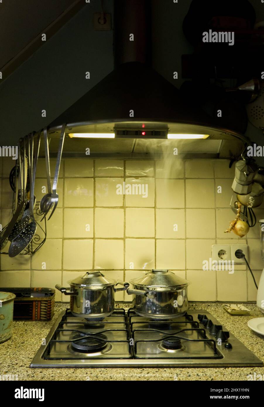 Meal preparation in the evening: pans on gas stove in kitchen by lamplight Stock Photo