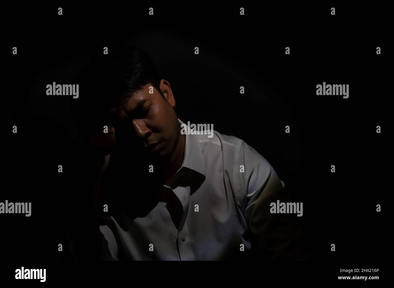 Asian depressed man sitting alone in dark background. Depression and mental health concept. Stock Photo