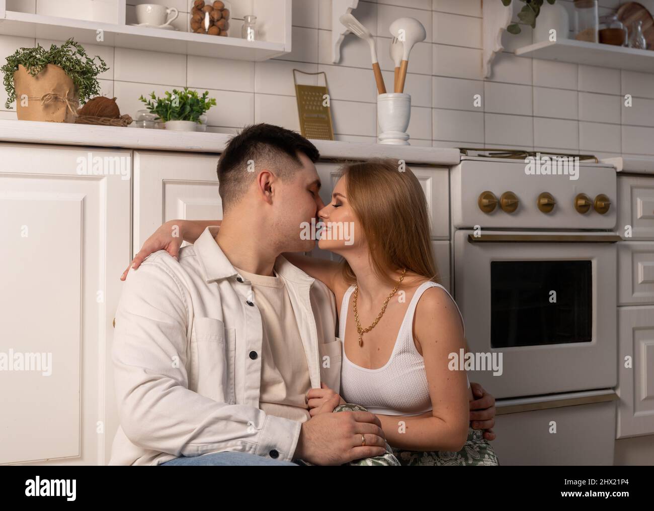 Married couple sitting on kitchen floor and kissing. Love and happiness in family relationship concept. High quality photo Stock Photo