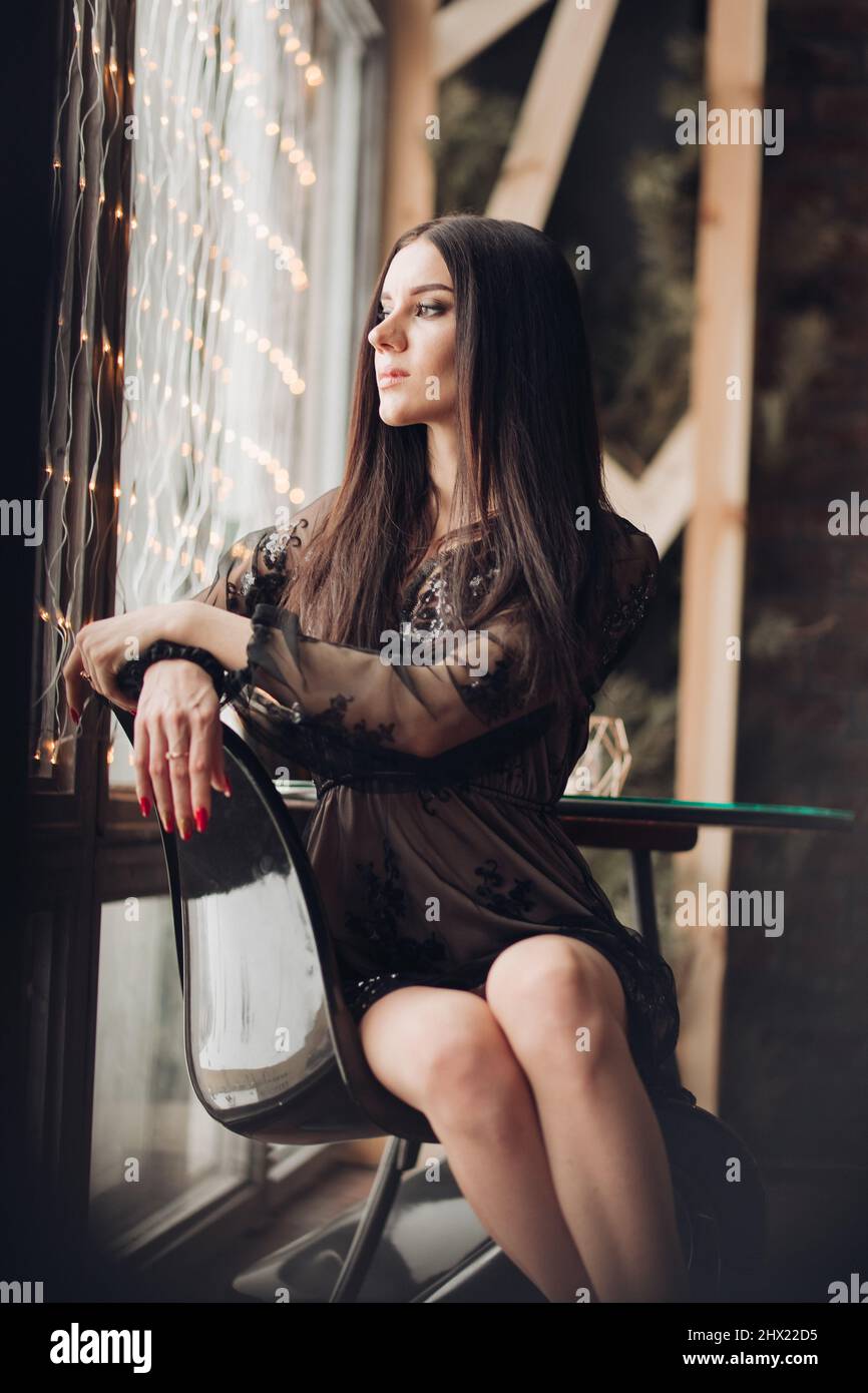 Gorgeous brunette model in black dress and heels in armchair Stock ...