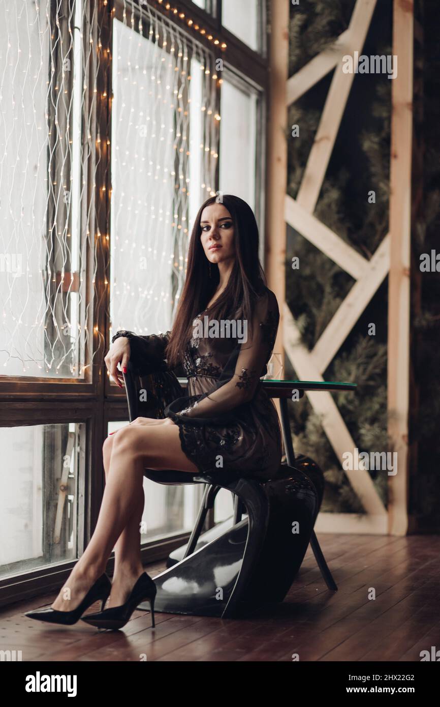 Gorgeous brunette model in black dress and heels in armchair Stock ...