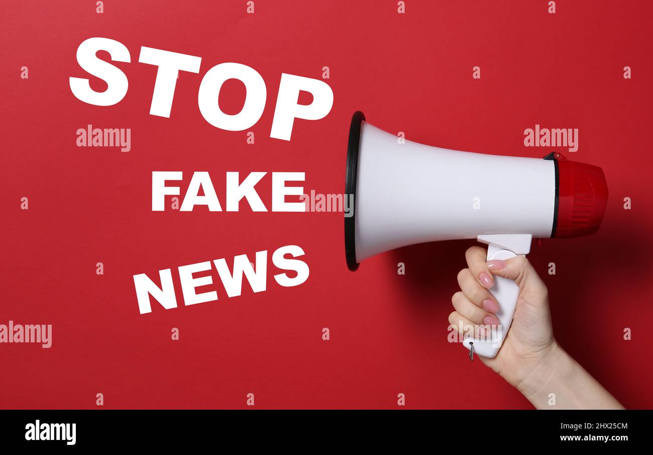 Female hand with megaphone and text STOP FAKE NEWS on red background ...