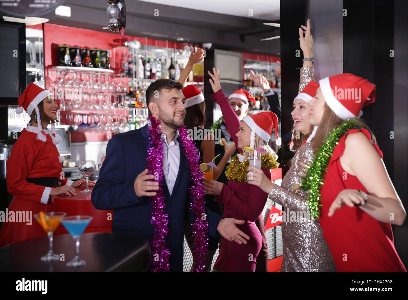 Man and two women in Santa hats celebrating at nightclub Stock Photo ...