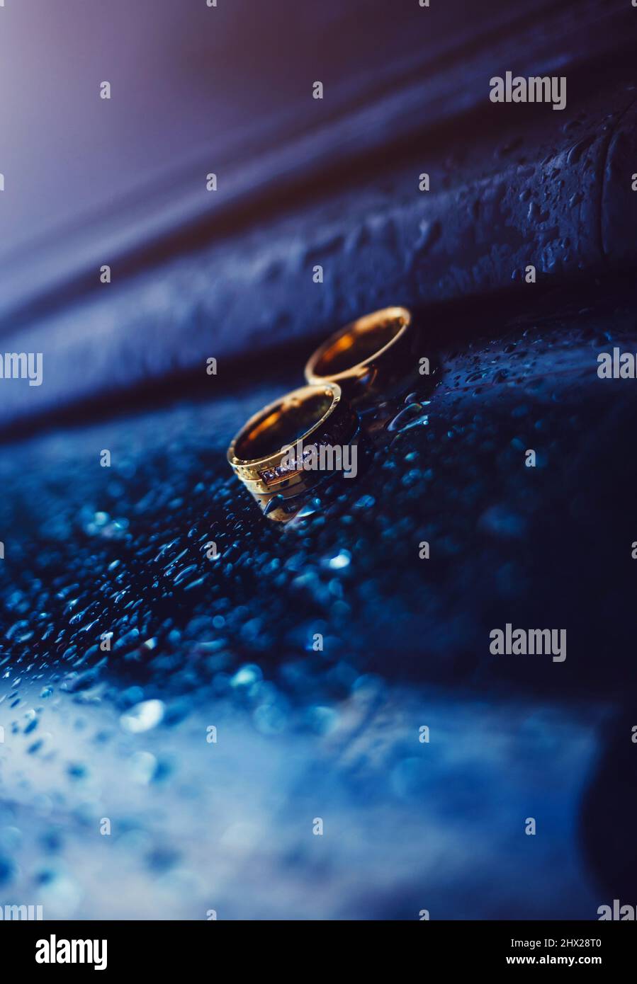 Two gold wedding rings on the car window with drops. symbol of love Stock Photo