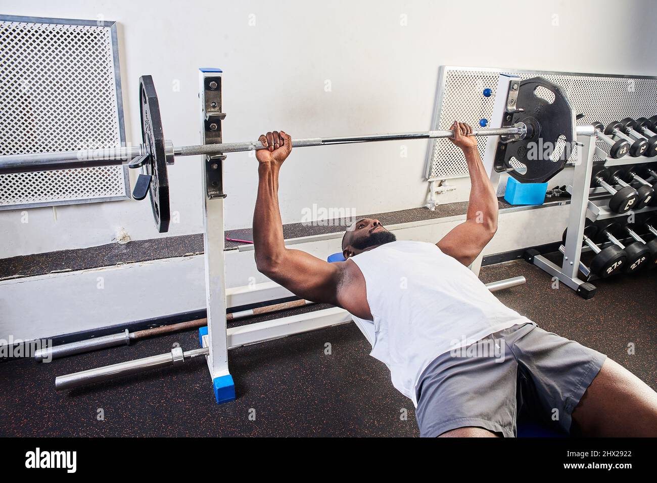 An African American man does a bench press lying on a bench in the gym