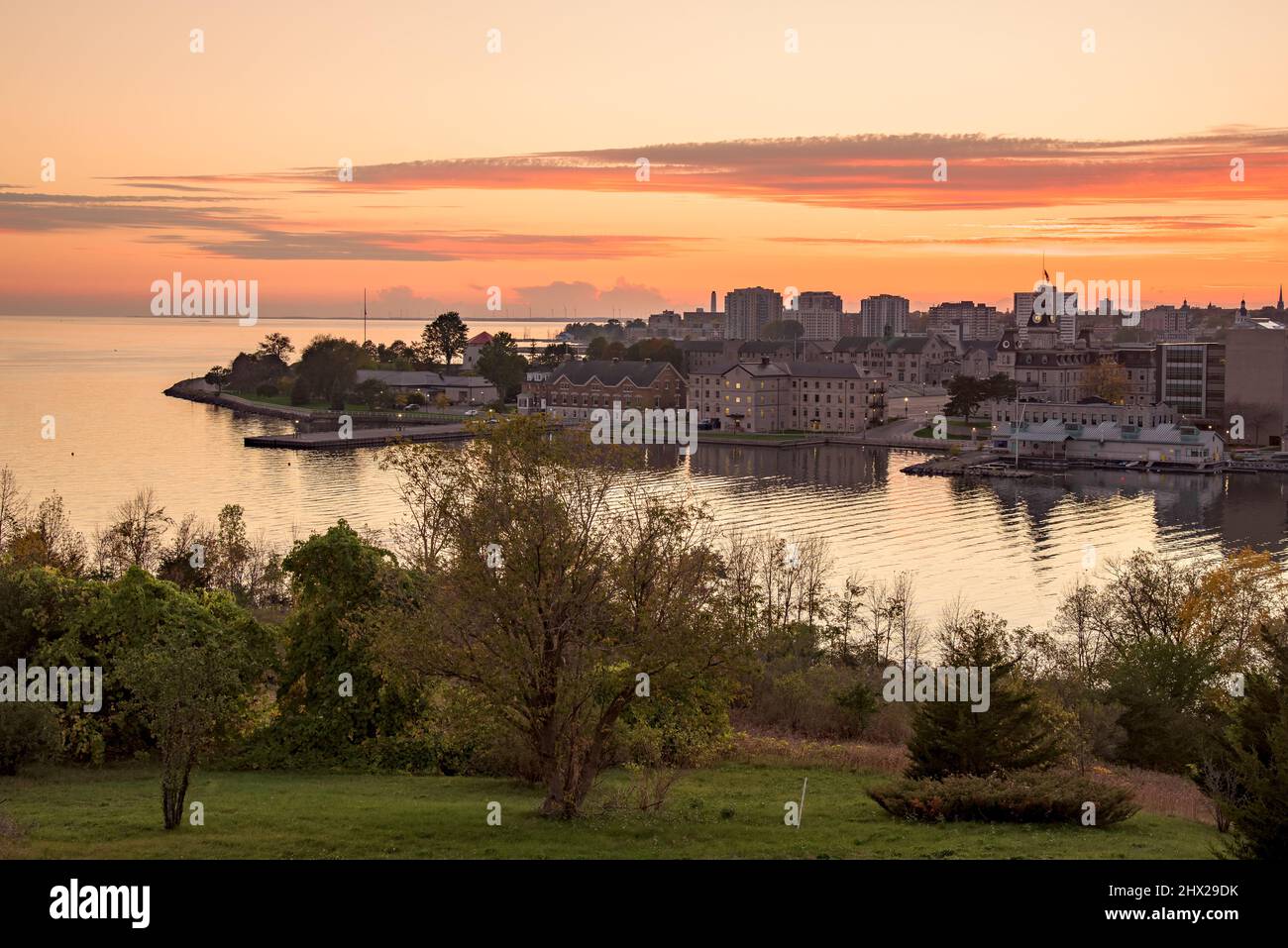 Autumn sunset over a city on the shores of a lake. An island with tall wind turbines is visible in background. Stock Photo