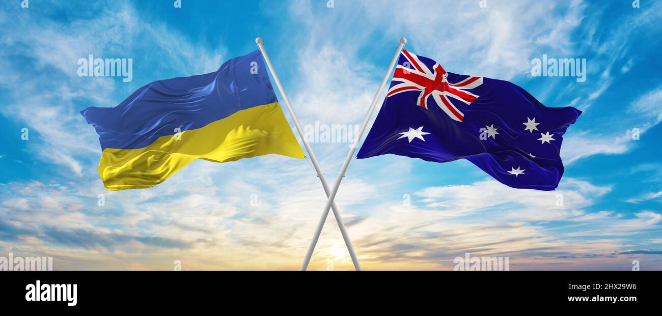 crossed national flags of Ukraine and Australia flag waving in wind at cloudy sky. Symbolizing relationship, dialog, travelling between two countries. Stock Photo