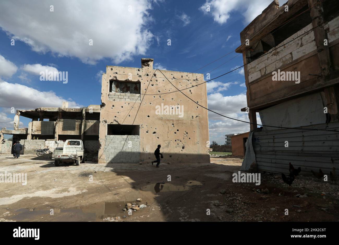 A boy walks past a damaged building in the rebel-held town of Tadef, on a frontline between Russian-backed Syrian government forces and Turkey-backed Syrian rebel-held territory, in northern Syria March 4, 2022. Picture taken March 4, 2022.  REUTERS/Khalil Ashawi Stock Photo