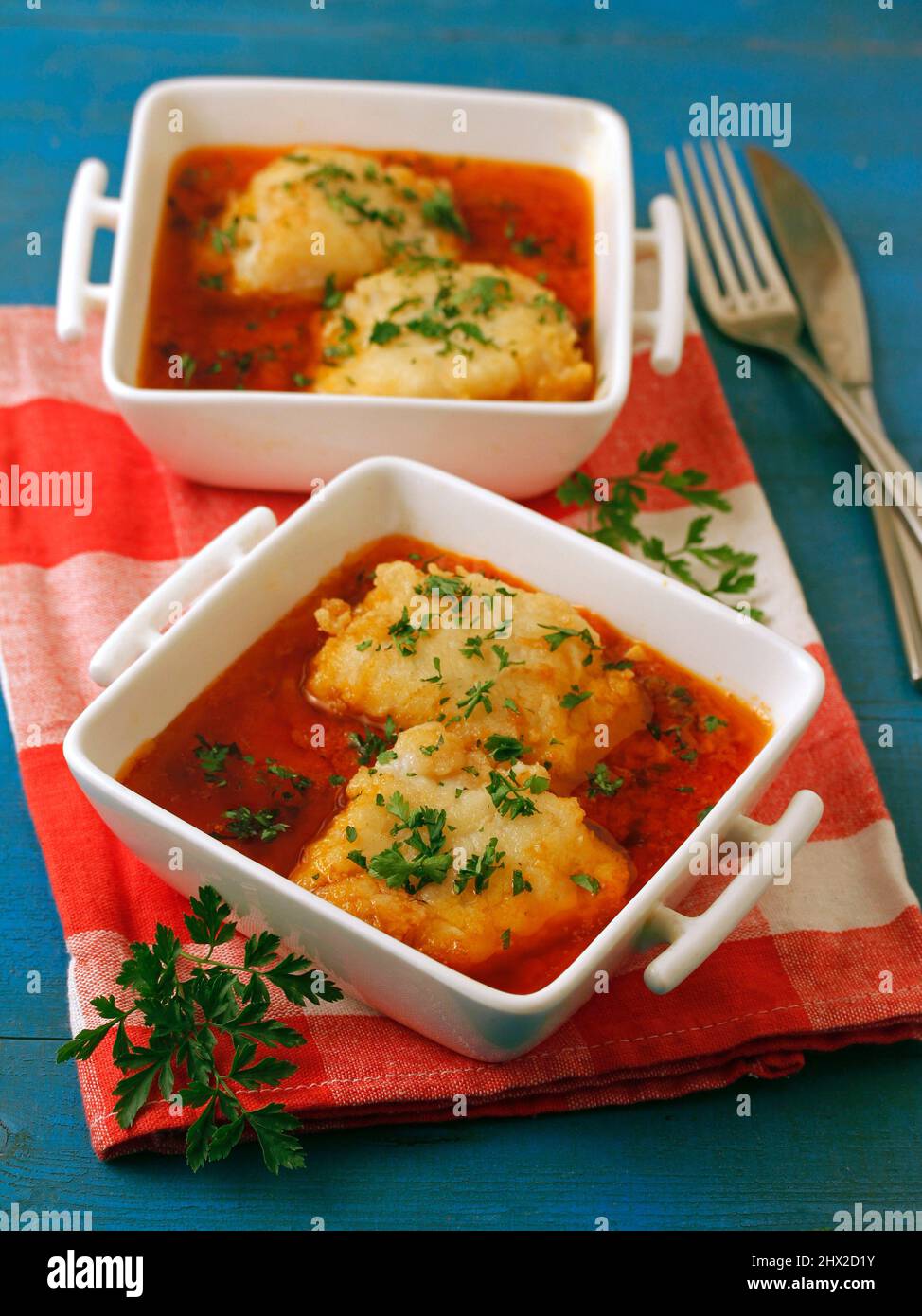 Cod fish with tomato sauce and parsley. Stock Photo