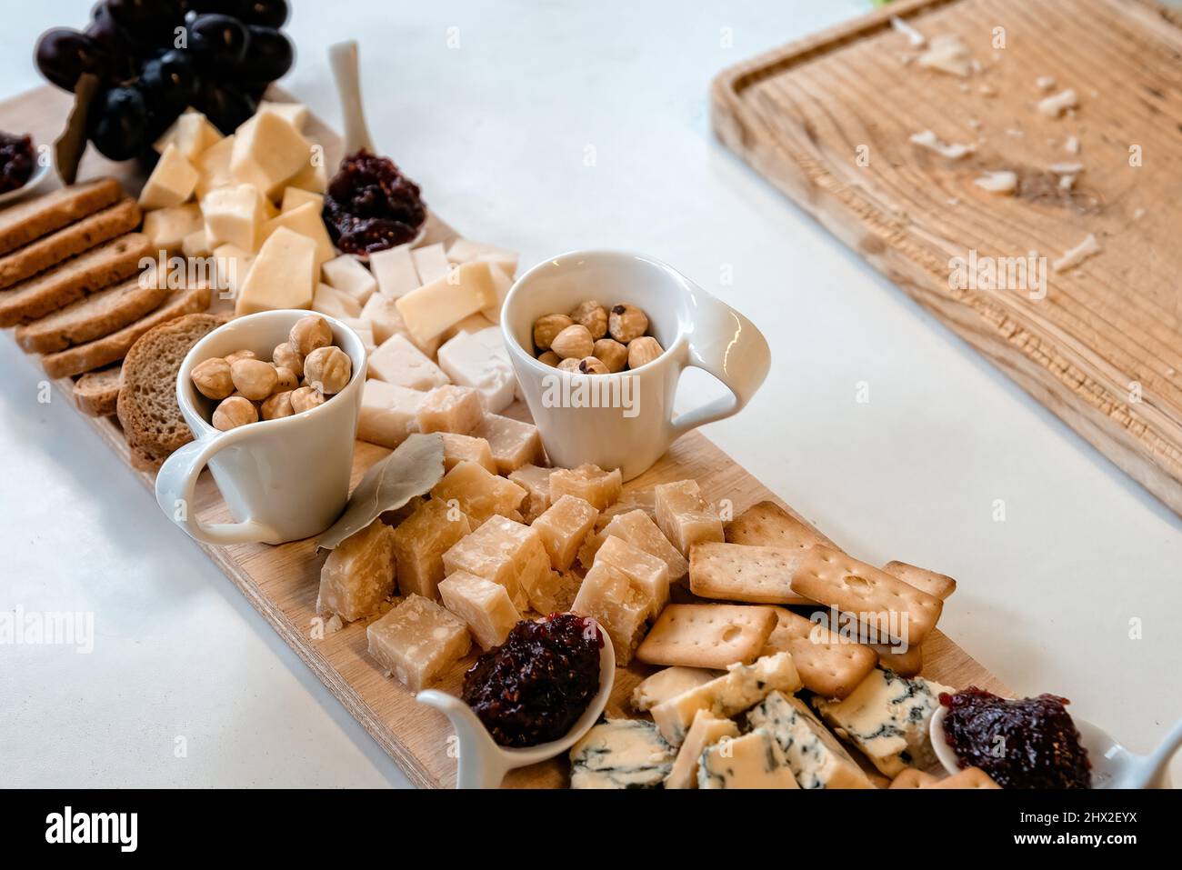 Cheeses selection with raspberry jeam and walnuts on rustic wooden table. Stock Photo