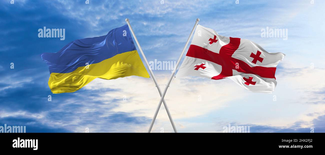 two crossed flags Georgia and Ukraine waving in wind at cloudy sky ...