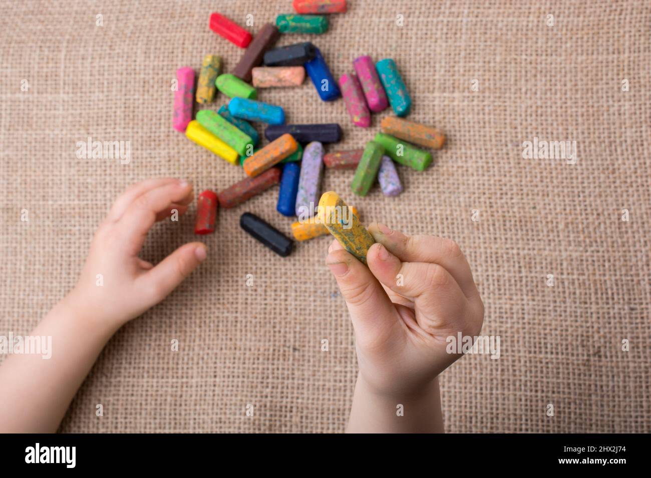 Used color crayons and a toddlers hand holding one Stock Photo Alamy