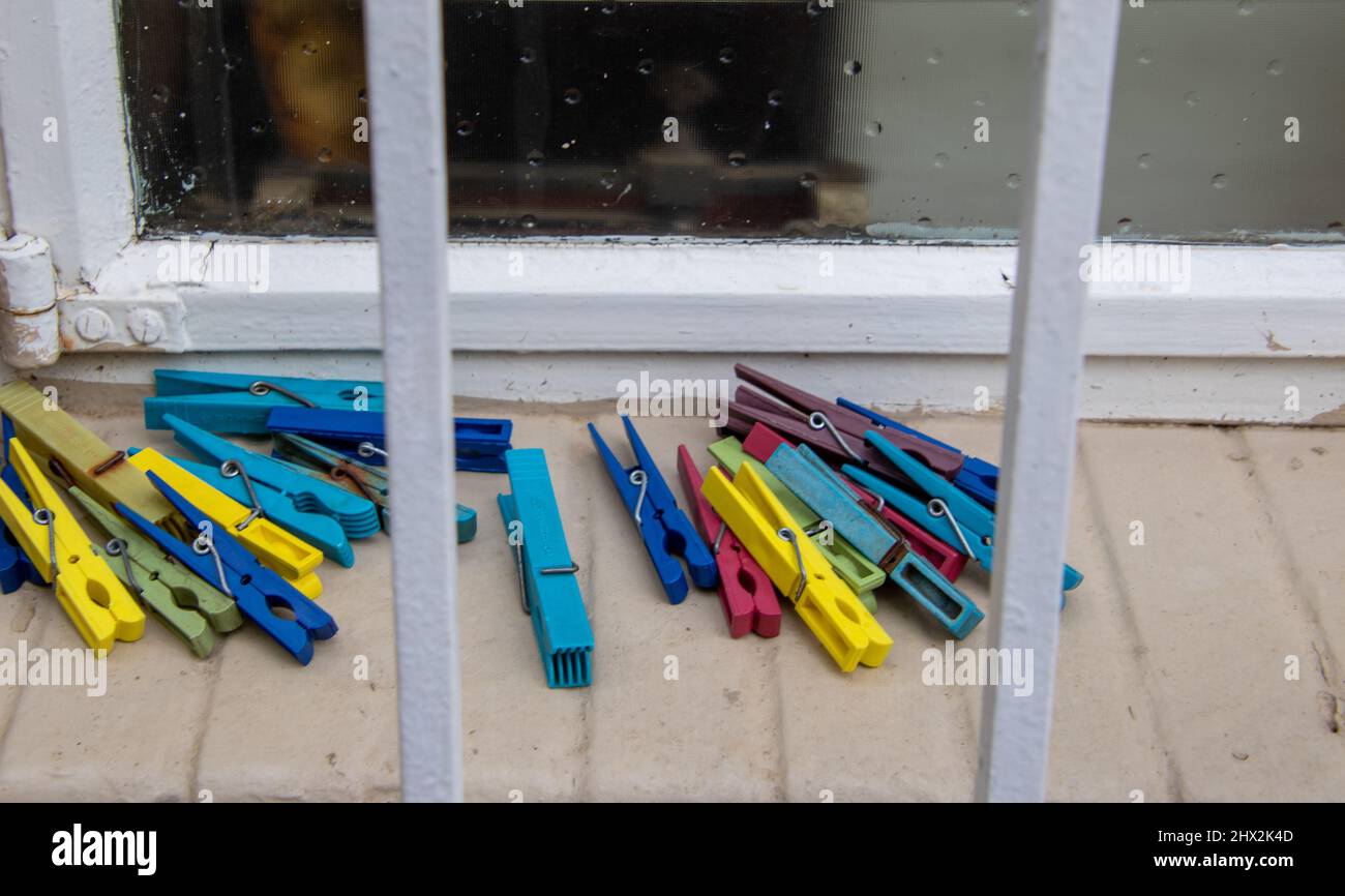 Colorful washing pegs lie on a window sill outside a house Stock Photo
