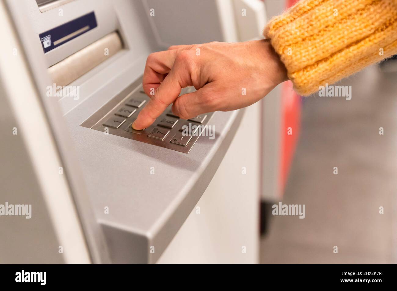Close up of a womans hand entering secret code on the keypad of an ATM machine. Stock Photo