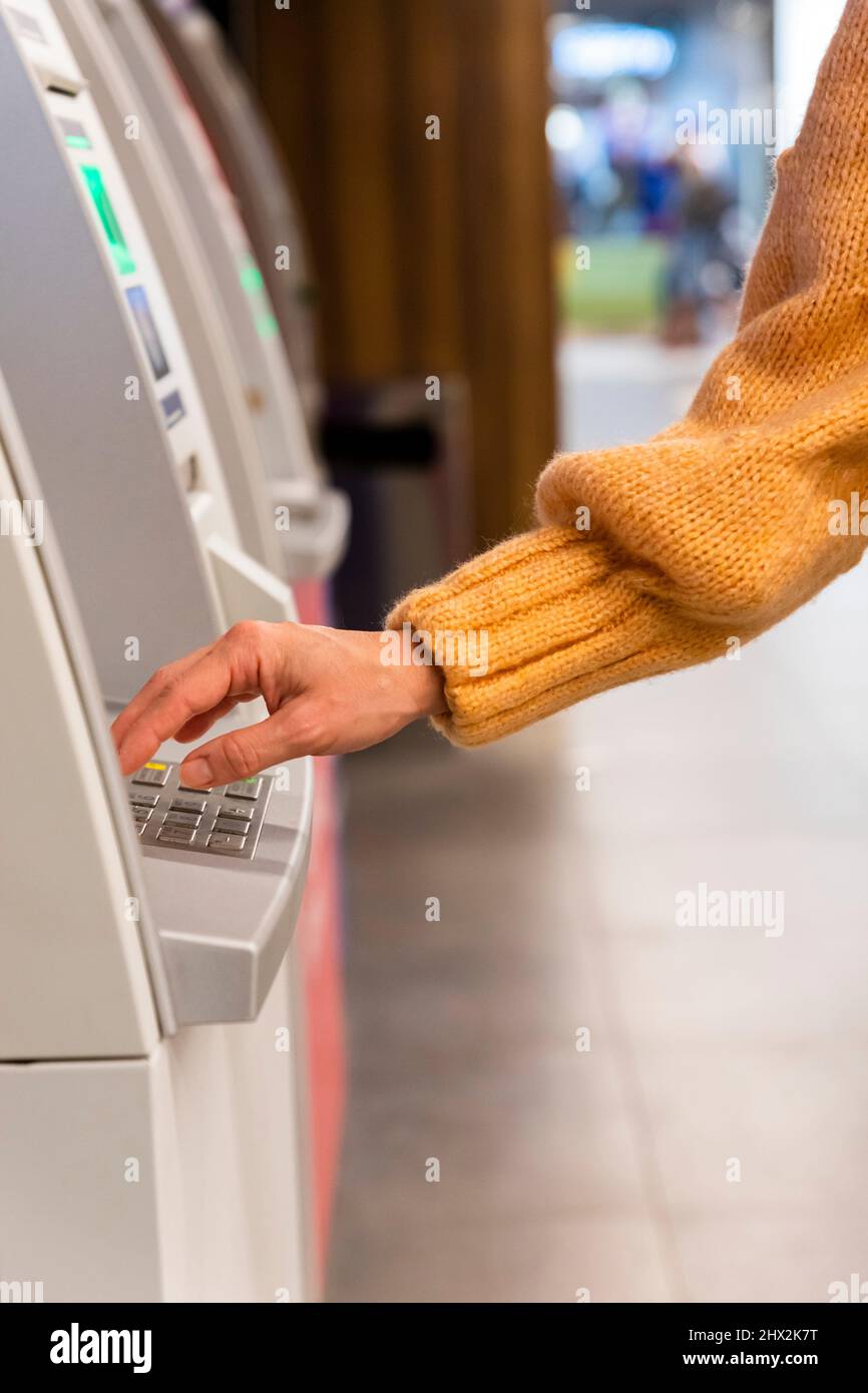 Close up of a womans hand entering secret code on the keypad of an ATM machine. Stock Photo