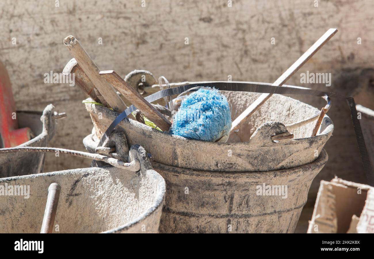 Plaster bucket full of very used construction tools. Selective focus. Stock Photo